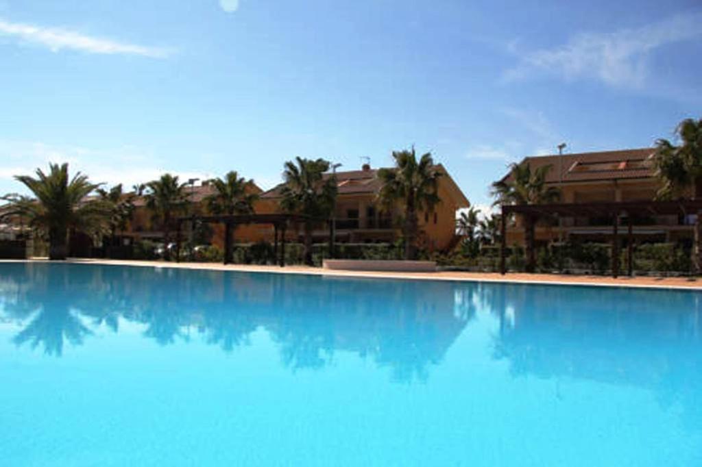 托雷法罗德玛尔吉住宅酒店的一座种植了棕榈树和建筑的大型蓝色游泳池