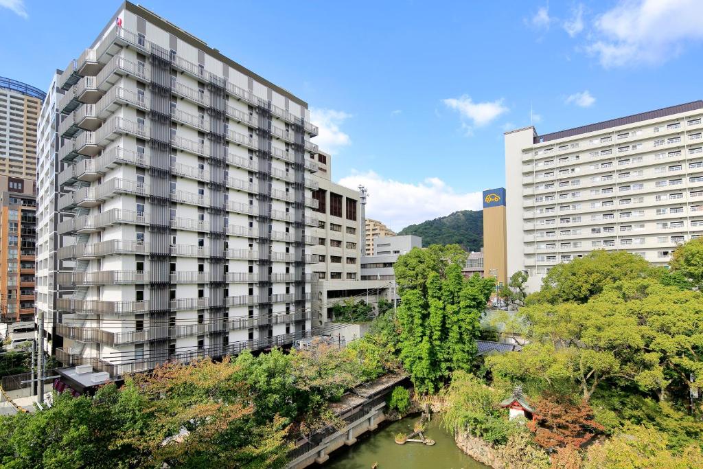 神户神户蒙特埃马纳酒店・艾美丽的一座高大的建筑,毗邻一条有建筑物的河流