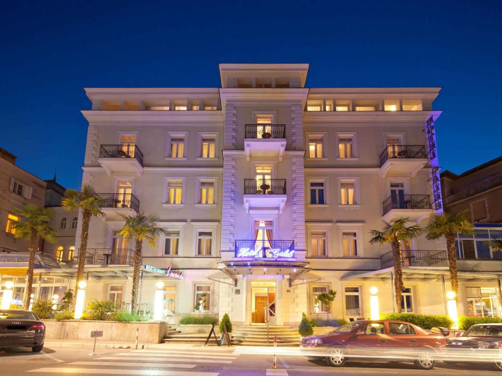 奥帕提亚加勒布酒店的一座白色的建筑,前面有汽车停放