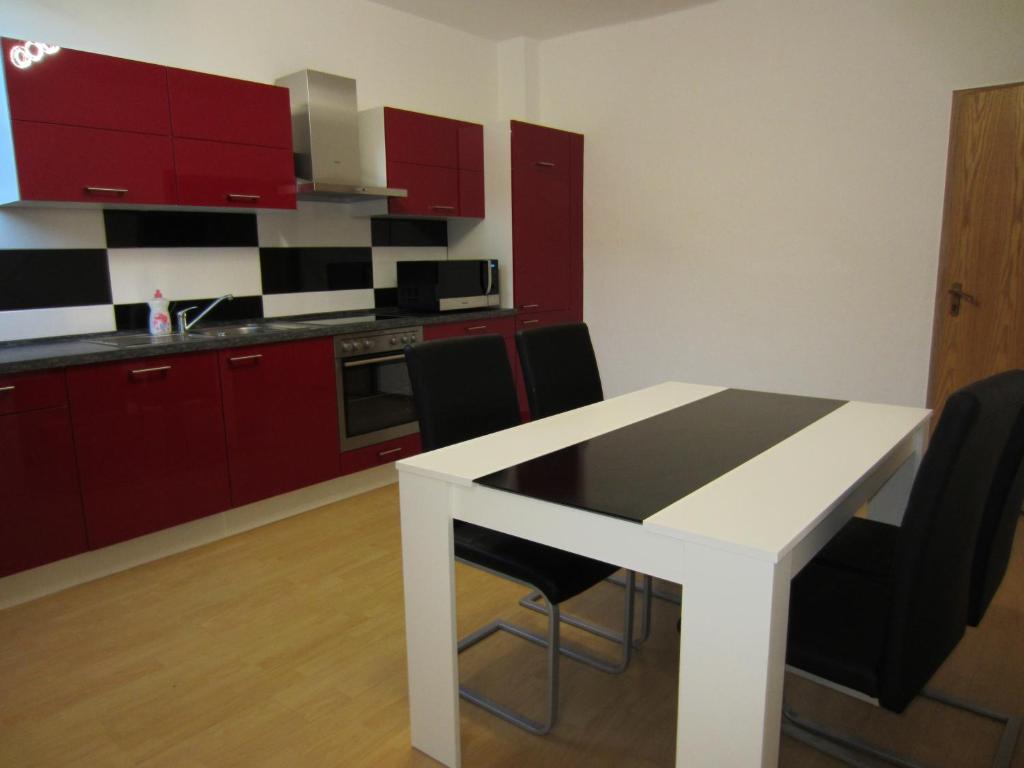 哈根Monteur Apartment Charlotte的厨房配有红色橱柜和白色的桌椅