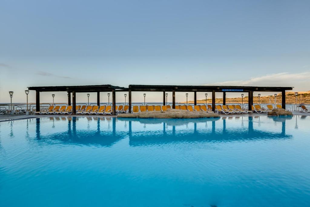 圣保罗湾城AX Sunny Coast Resort & Spa的一座带椅子的大型蓝色海水游泳池和一座建筑