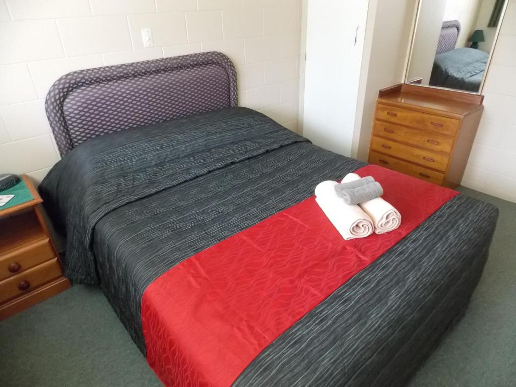 朗伊奥拉Rangiora Lodge Motel的一间卧室配有一张带红色毯子和镜子的床