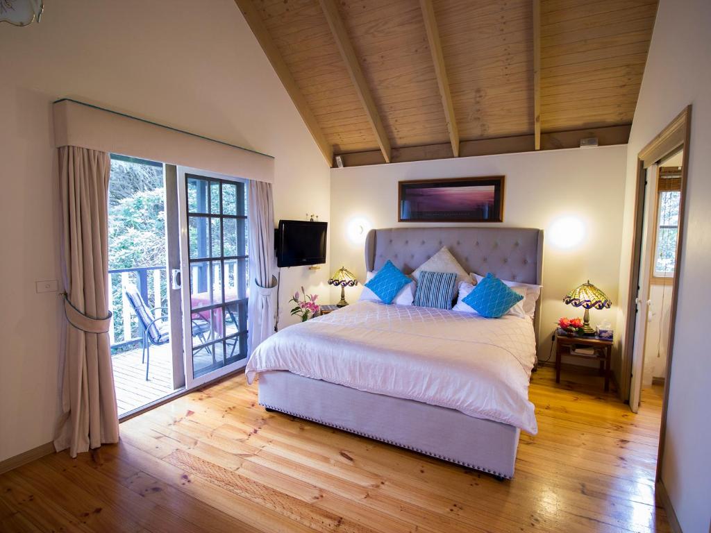 奥林达奥林达乡村小屋酒店的一间带大床的卧室和一个阳台