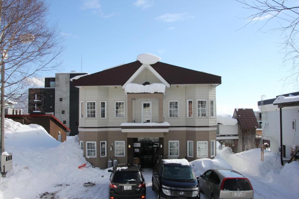 二世古Absolute Niseko Lodge的一座大建筑,里面装有汽车停在雪上