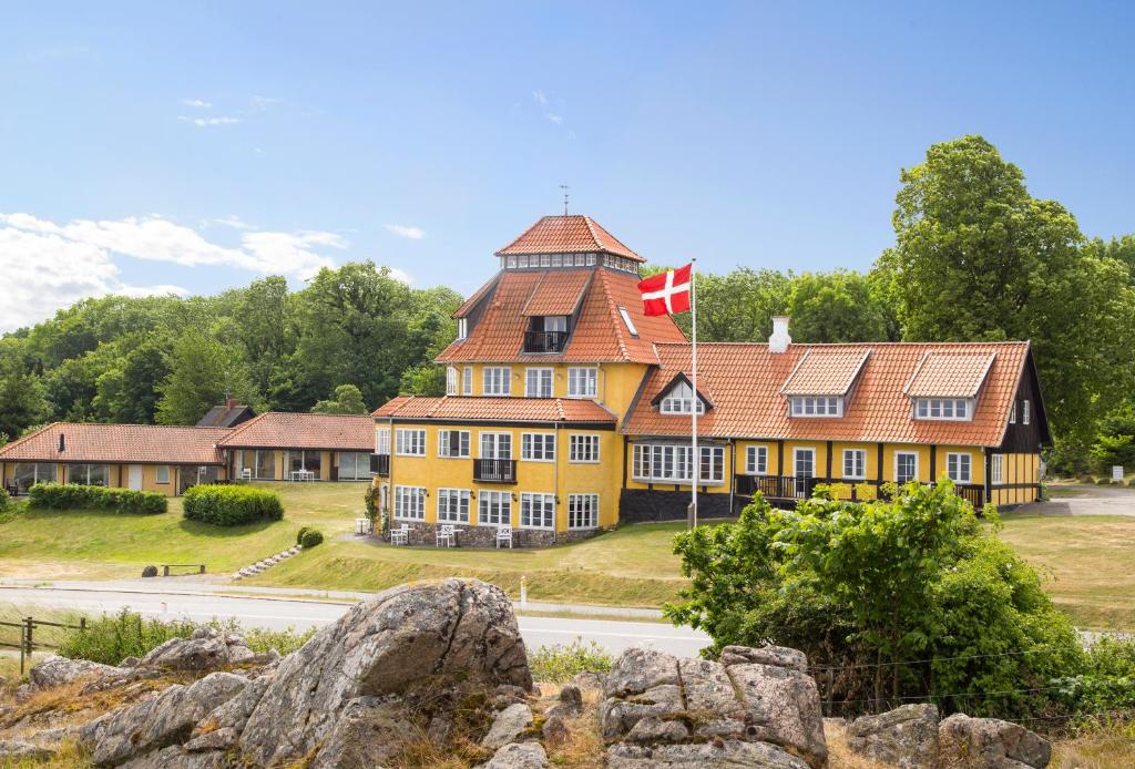 Bådsted斯塔莫巴德酒店的一座黄色的大建筑,上面有藤旗