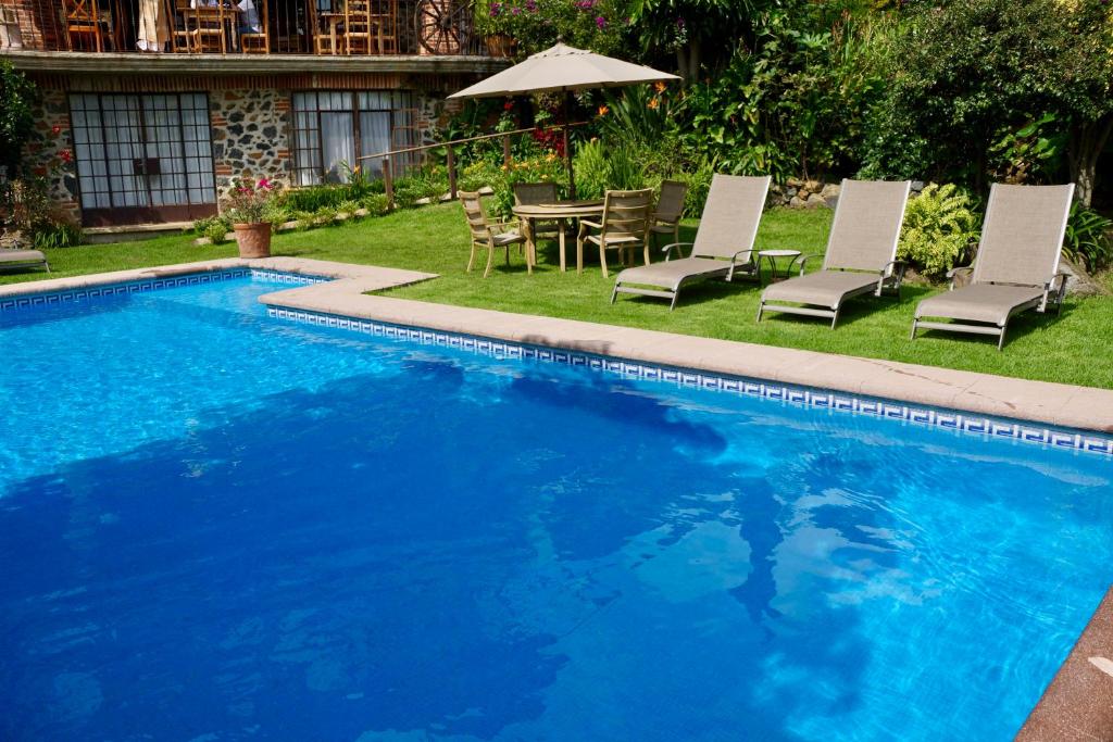 迪坡斯特兰Hotel Casa del Angel的一个带椅子和桌子的游泳池以及一把遮阳伞