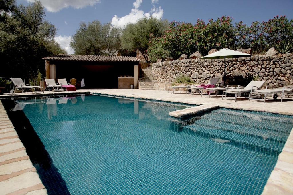 埃斯波尔莱斯Agroturismo Can Torna AG178的庭院内的游泳池配有椅子和遮阳伞