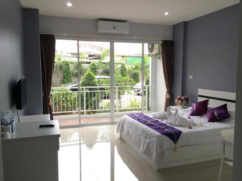 北芭堤雅Pandora House by Mike Group的一间卧室配有一张带紫色枕头的床和一个阳台