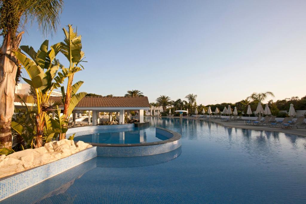 阿依纳帕克里斯托菲娜酒店的棕榈树和椅子的度假村的游泳池