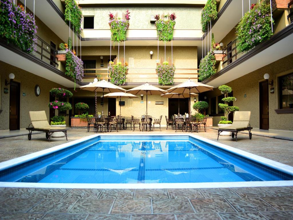 科尔多瓦Hotel Layfer del Centro, Córdoba, Ver的一座位于酒店庭院的游泳池,配有桌子和遮阳伞
