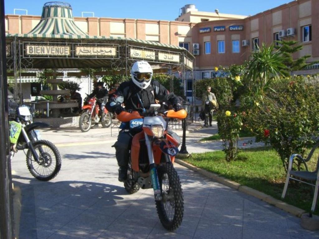 SelouaneMotel Paris Dakar的骑摩托车的人沿着人行道骑着摩托车