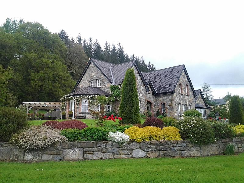 利特里姆Drumhierney Lodge的院子中一座石头墙和鲜花的房子