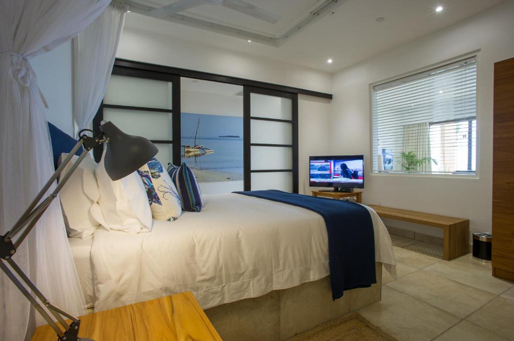 达累斯萨拉姆The Oyster Bay Hotel Suites的一间卧室设有一张带电视和窗户的床。