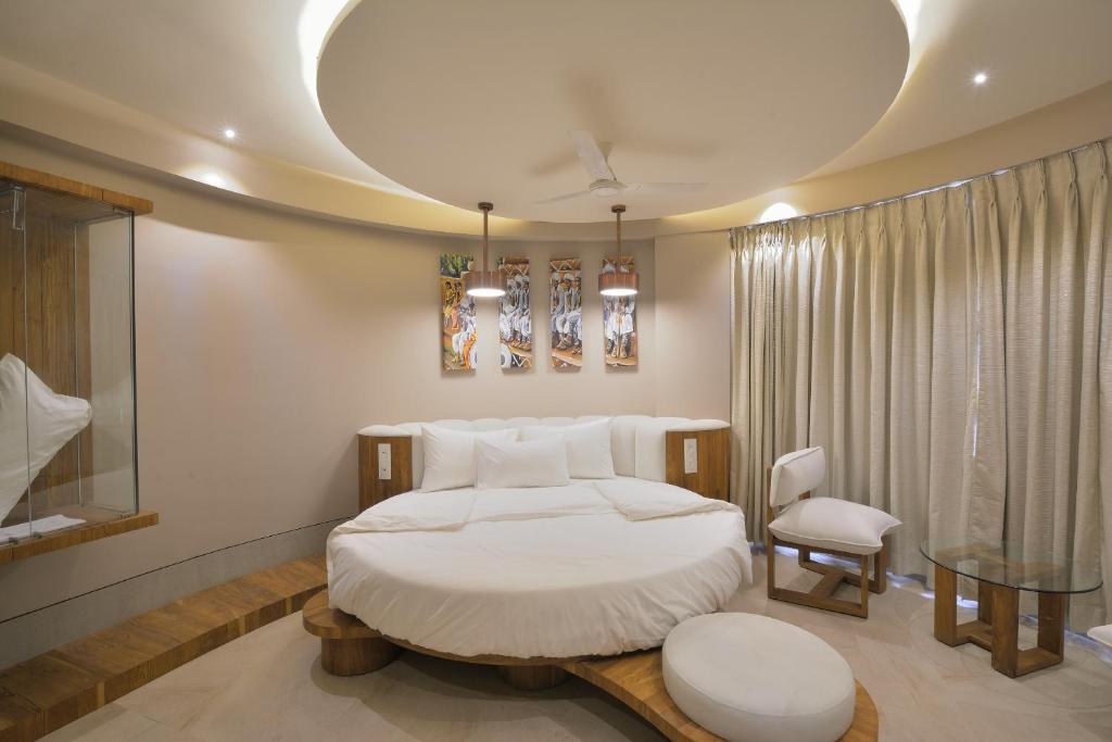 艾哈迈达巴德文雅酒店的卧室配有1张床、1张桌子和1把椅子