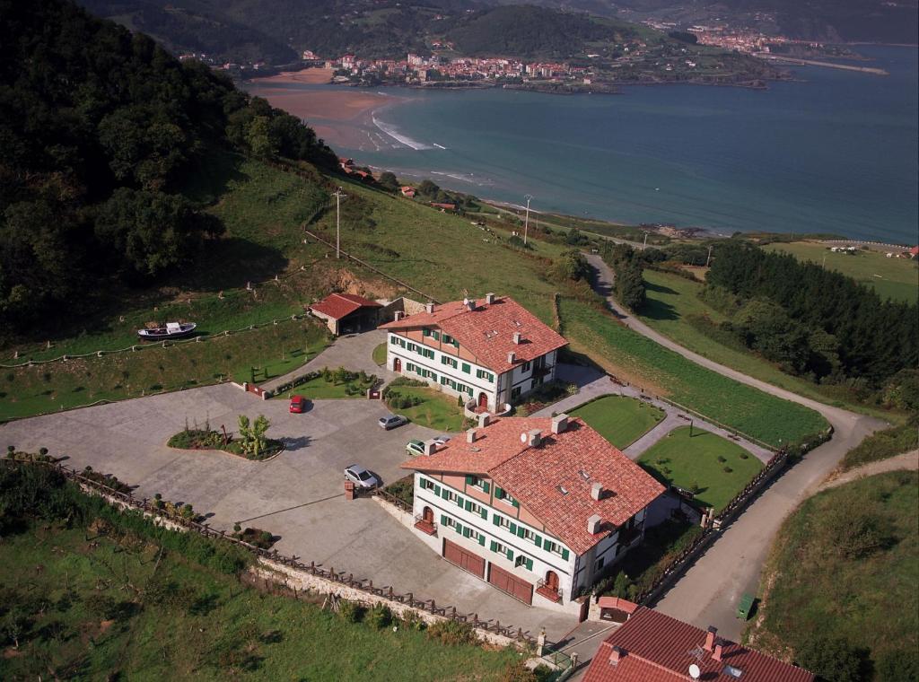 伊巴兰格鲁Hotel Spa Gametxo的水边山丘上房屋的空中景观
