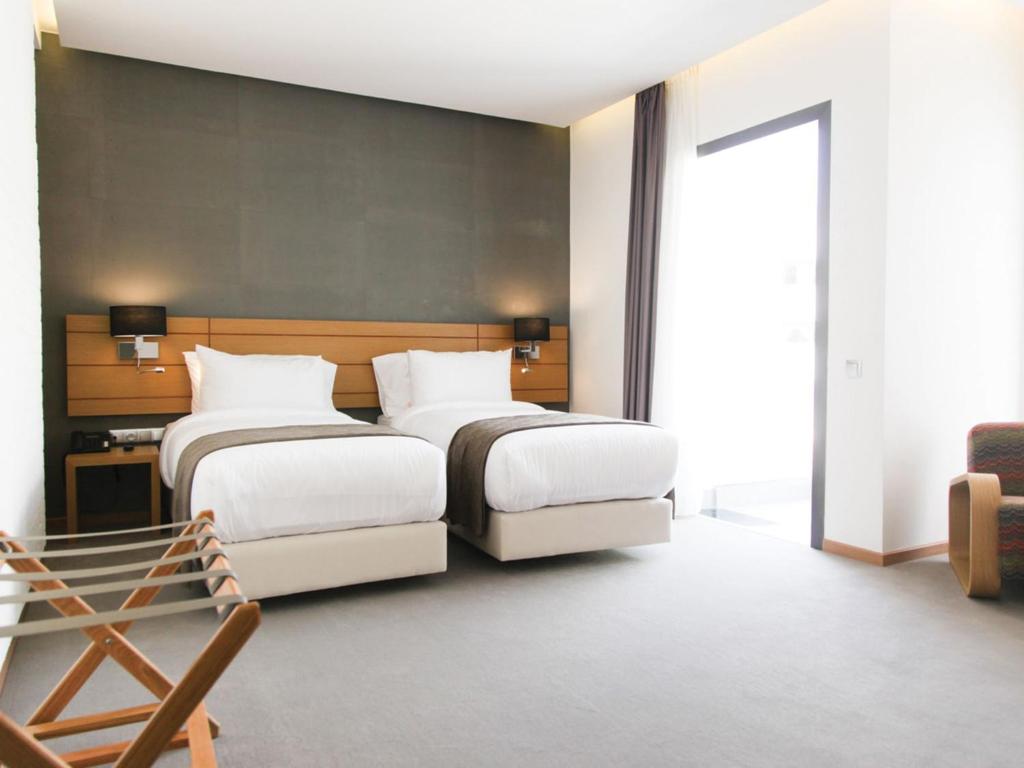 拉巴特Smarts Hotel Agdal Rabat的酒店客房,配有两张床和椅子