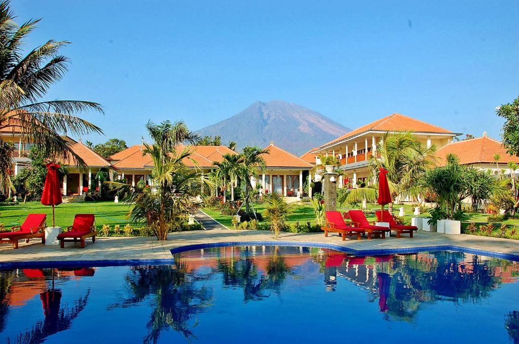 图兰奔巴厘岛潜水度假及Spa酒店的一个带红色椅子的游泳池和一个山地的度假胜地
