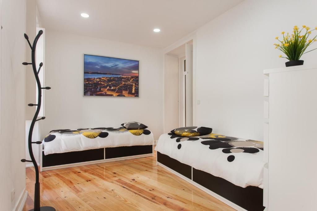 里斯本精英旅馆的配有白色墙壁和木地板的客房内的两张床