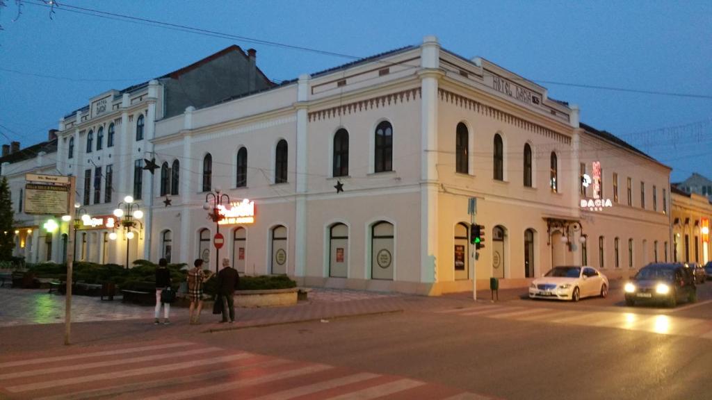 卢戈日Hotel Dacia的夜行的街道上一座白色的大建筑