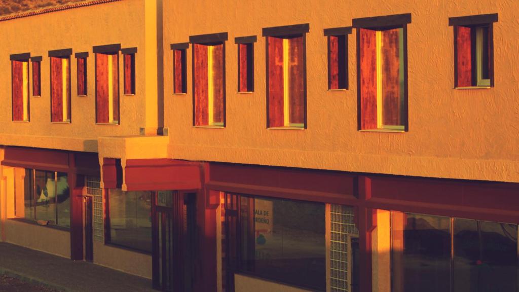 埃林Hotel Bella Hellín的一座橙色的建筑,在建筑的一侧设有红色窗户