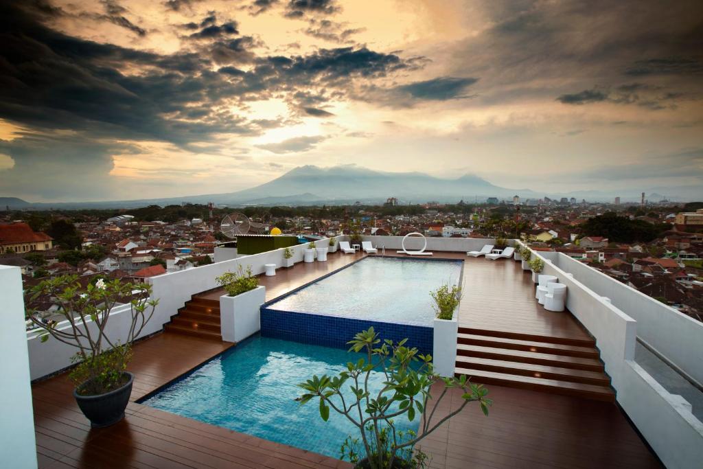 玛琅Ascent Hotel & Cafe Malang的从带游泳池的建筑屋顶上欣赏美景