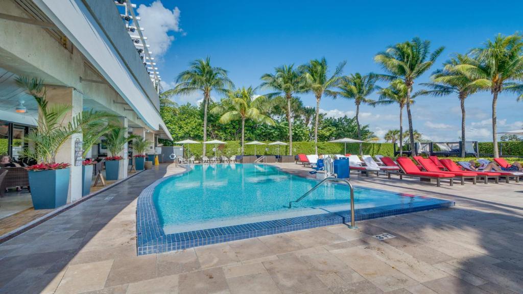 迈阿密海滩Miami Beachfront Bentley Hotel Studio Condo with Balcony的一个带椅子和棕榈树的度假村游泳池