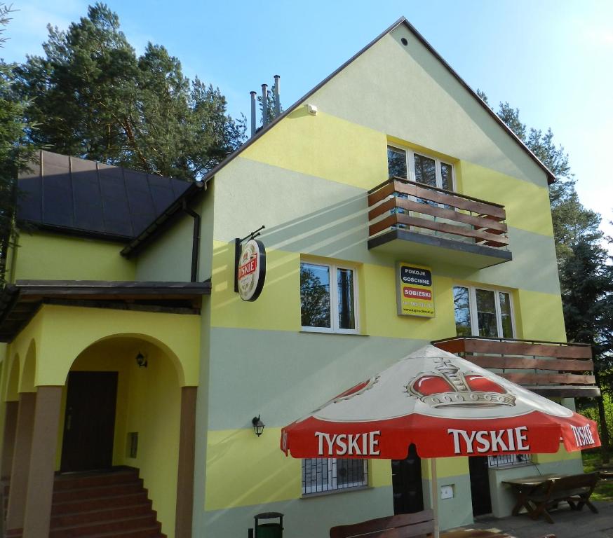 SobieskiPokoje Gościnne Przystań KAJA w Sobieskach nad Wkrą的黄色的建筑,带有雨伞和树冠