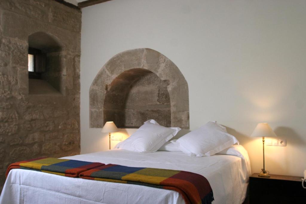 新阿森西奥拉卡贝加尼亚酒店的一间卧室设有一张带石墙的大床