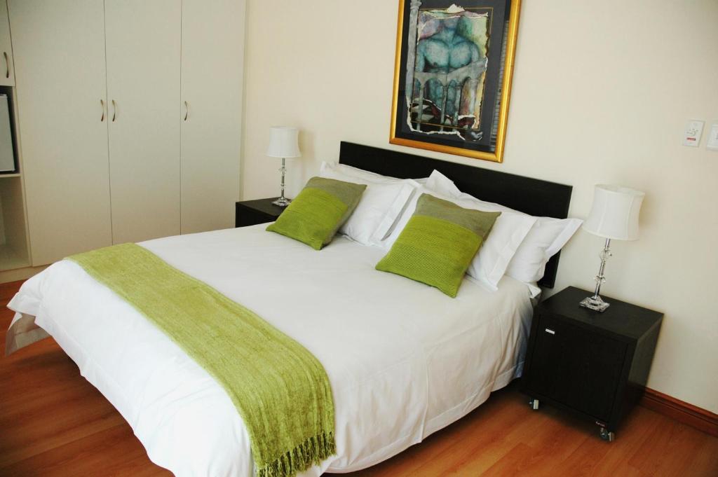 斯泰伦博斯Edelweiss Bed & Breakfast的卧室配有带绿色枕头的大型白色床