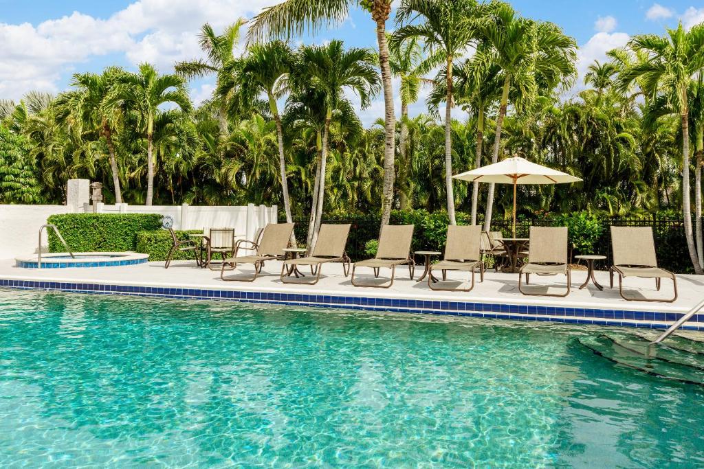 马可岛奥尔德马可岛套房及宾馆的一个带椅子和遮阳伞的游泳池,并种植了棕榈树