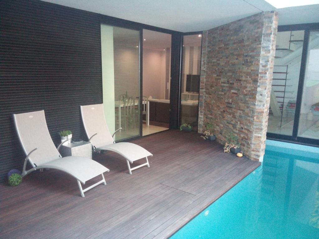 厄米森德Oporto Guesthouse Ermesinde的砖墙旁的一个带两把白色椅子的游泳池