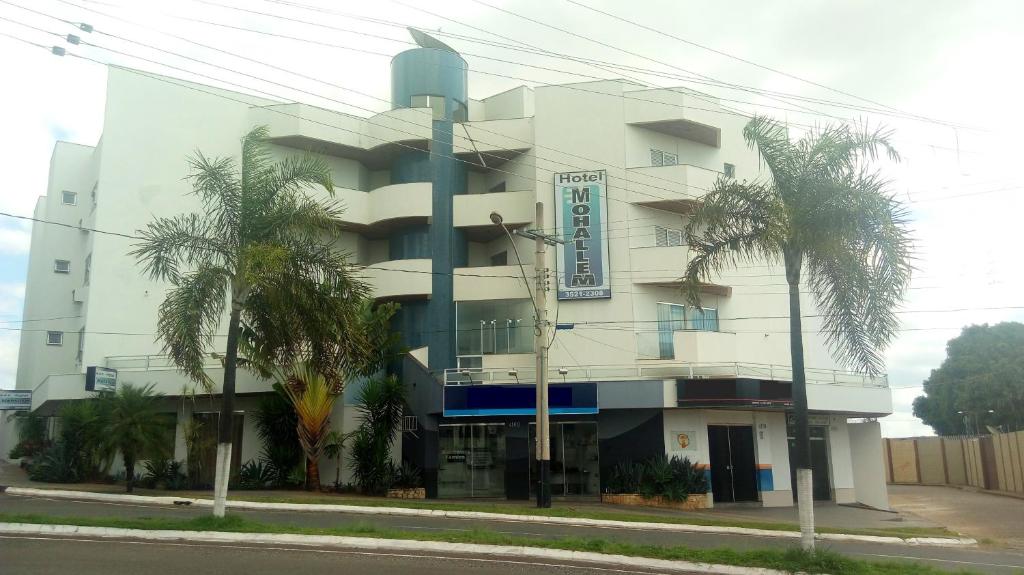 帕苏斯莫哈尔姆酒店的一座白色的建筑,前面有棕榈树