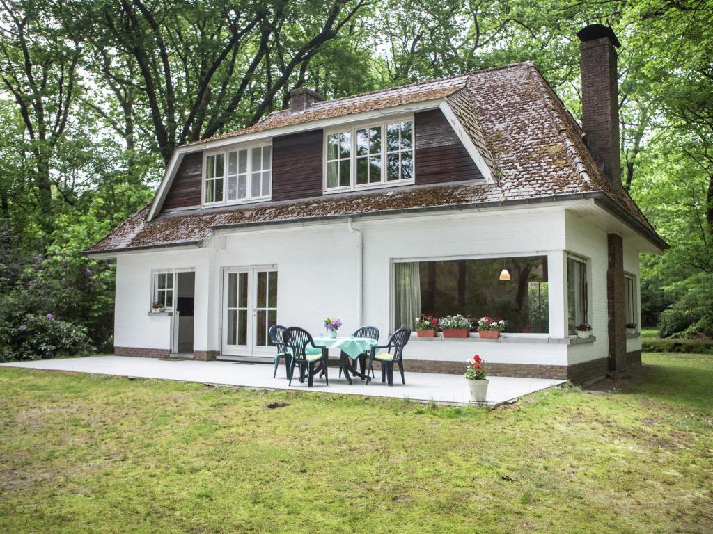 ZoerselThis atmospheric holiday home的白色的小房子,配有桌子和椅子