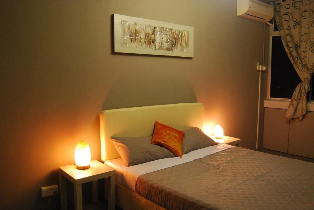 古晋Borneo Sweet Guesthouse的一间卧室配有一张带两个灯的床