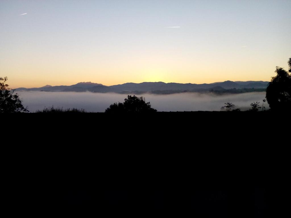 圣塞瓦斯蒂安Casa Rural Aristondo Agroturismo的享有雾 ⁇ 的田野和日落美景