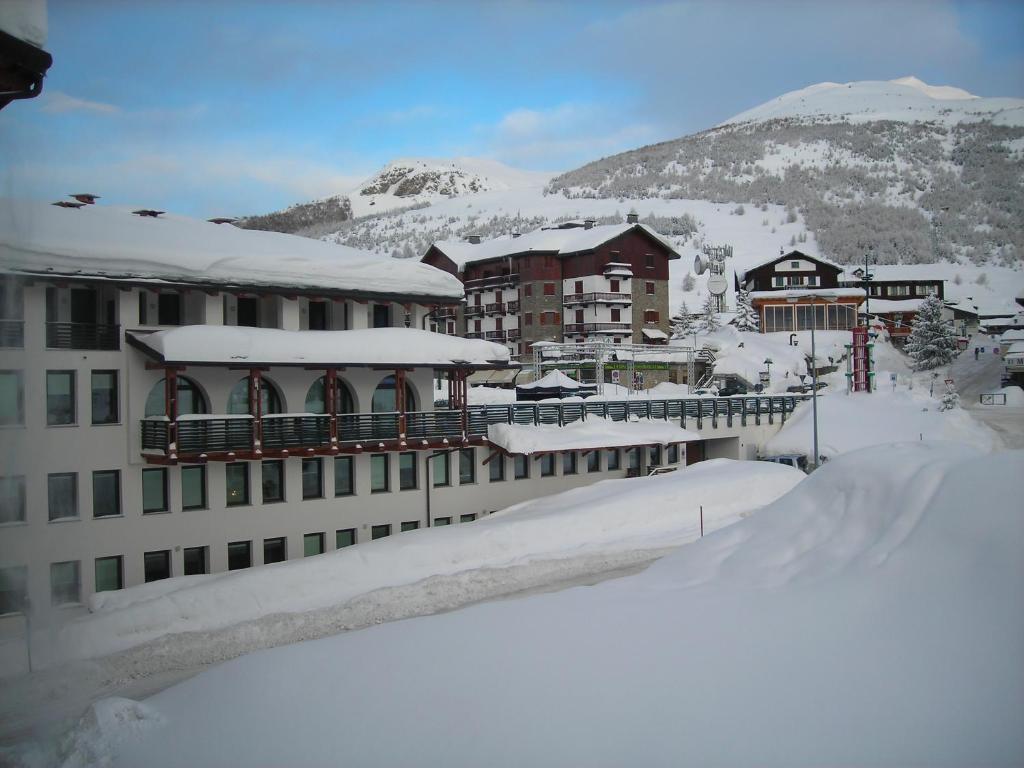 塞斯特雷Torre Dell'orologio Apartment的一座被雪覆盖的建筑,背景是一座山