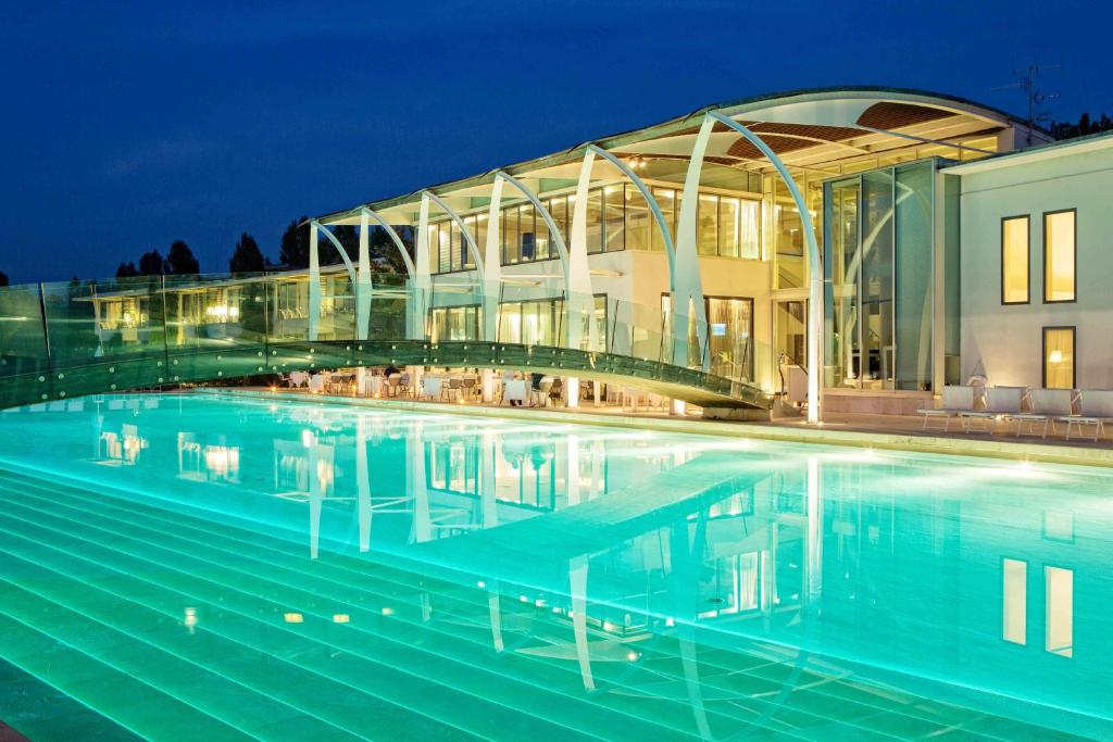 圣乔瓦尼-因马里尼亚诺海滨高尔夫度假酒店的一座游泳池,在晚上在建筑物前