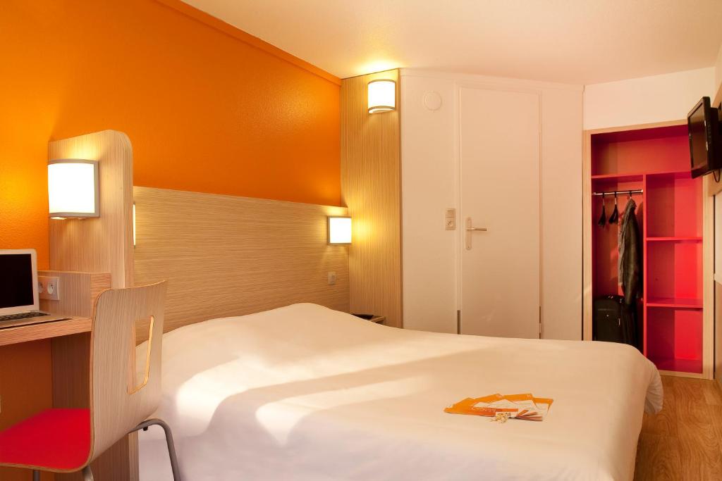莱斯托雷特斯Première Classe Montélimar Nord的酒店客房带白色的床和红色椅子