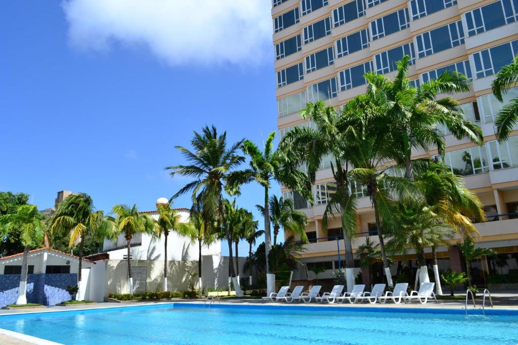 波拉马尔Hotel Faranda Express Puerta del Sol Porlamar的棕榈树酒店前的游泳池