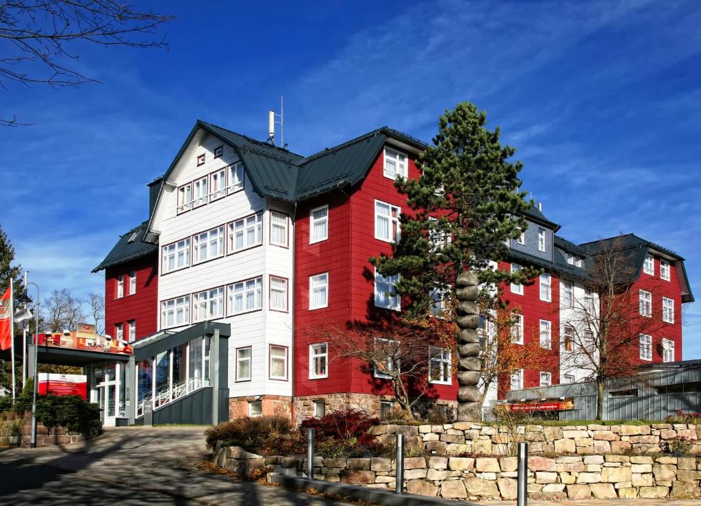 奥伯霍夫Konsumhotel Oberhof - Berghotel Oberhof的一座红白的建筑,前面有一棵树