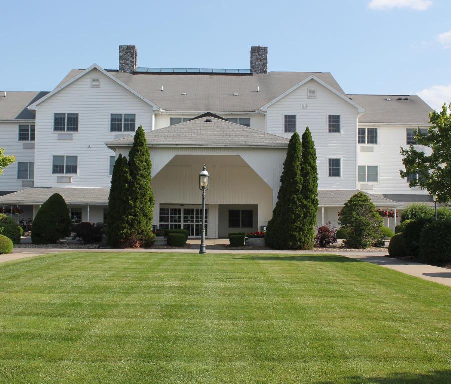西普谢瓦纳Farmstead Inn and Conference Center的一座带绿色草坪的大型白色房屋