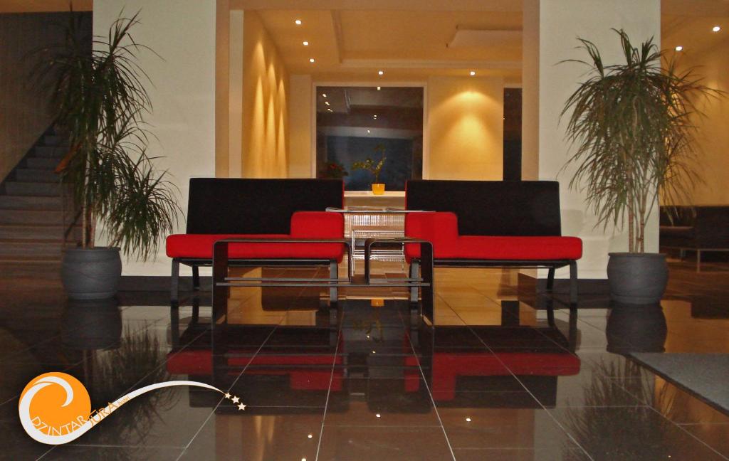 文茨皮尔斯金塔如拉酒店的大堂设有2把红色椅子和1张玻璃桌