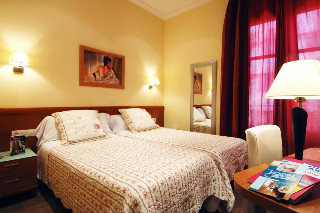 巴塞罗那奥尔良旅馆的酒店客房配有一张床和一张带台灯的桌子