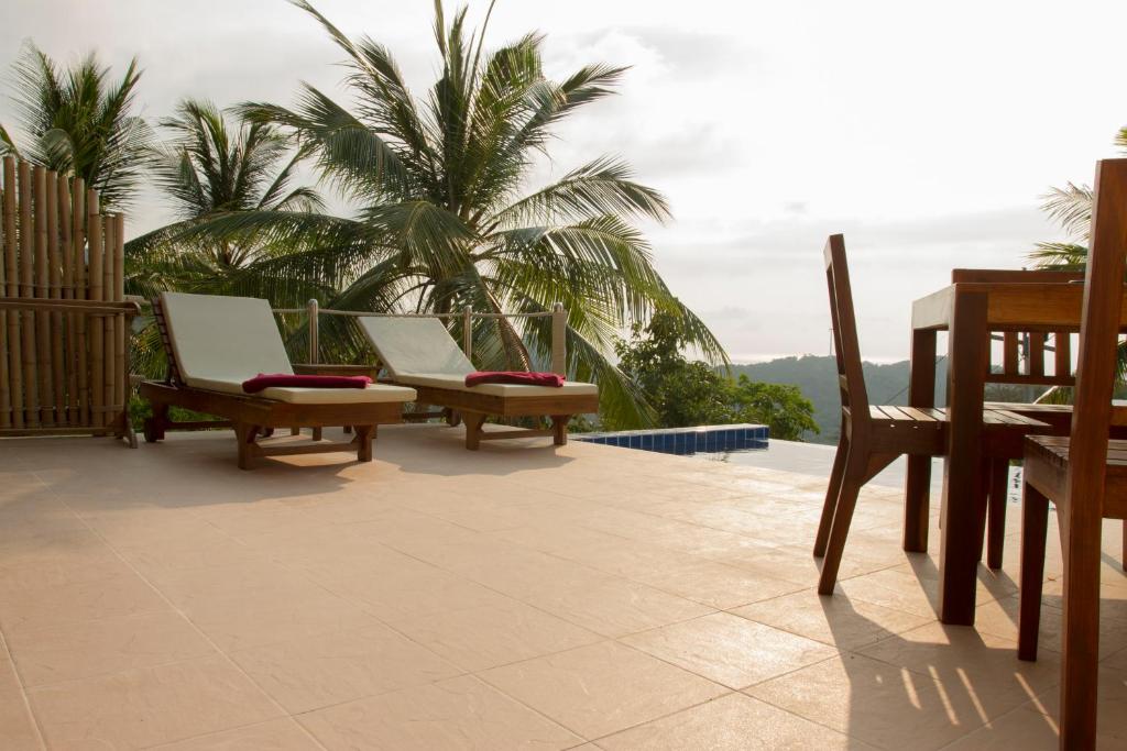 涛岛卡罗别墅的庭院的后面设有两把椅子和棕榈树