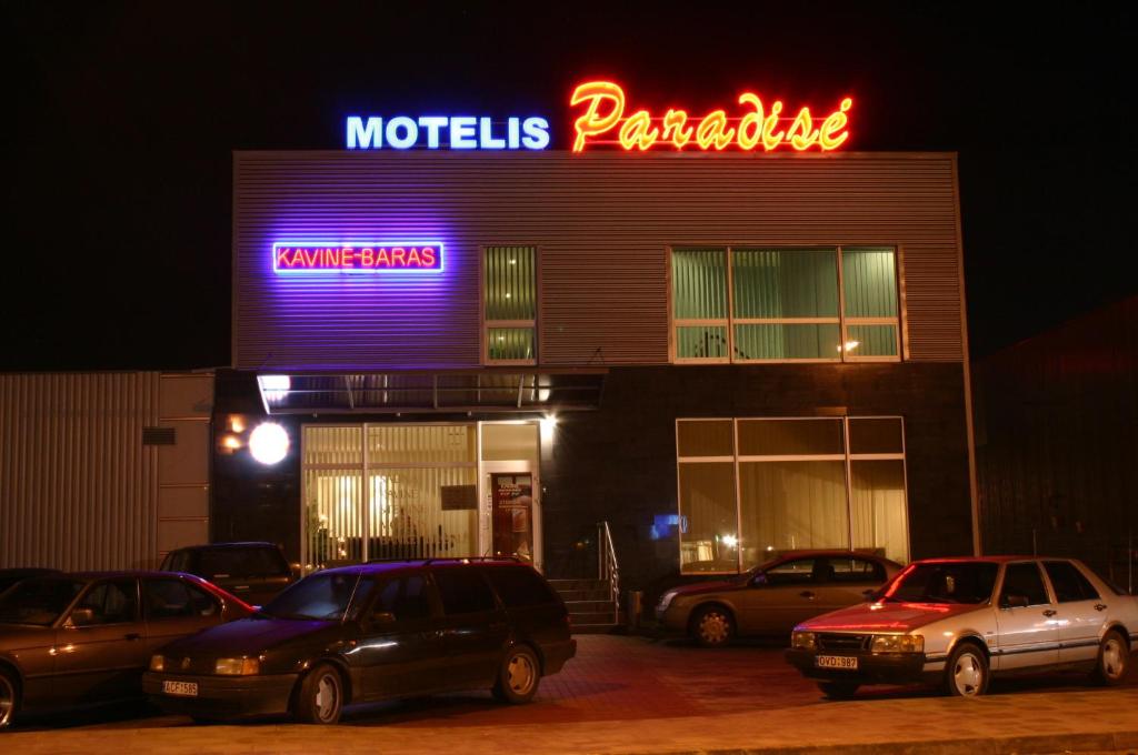 维尔纽斯天堂汽车旅馆的一座有汽车在晚上停在停车场的建筑