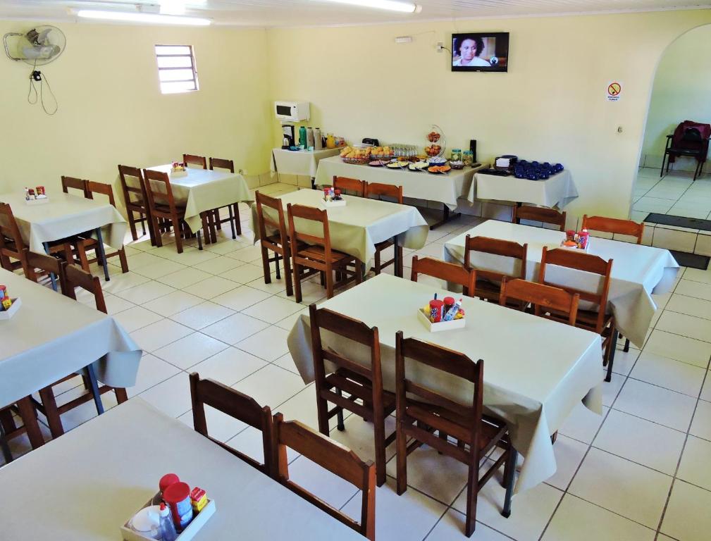 圣安娜-利弗拉门图Hotel Comodoro De Livramento的用餐室配有白色的桌子和木椅