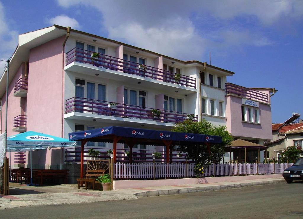 洛泽内茨Hotel Strajica的粉红色的建筑,在街上设有紫色阳台