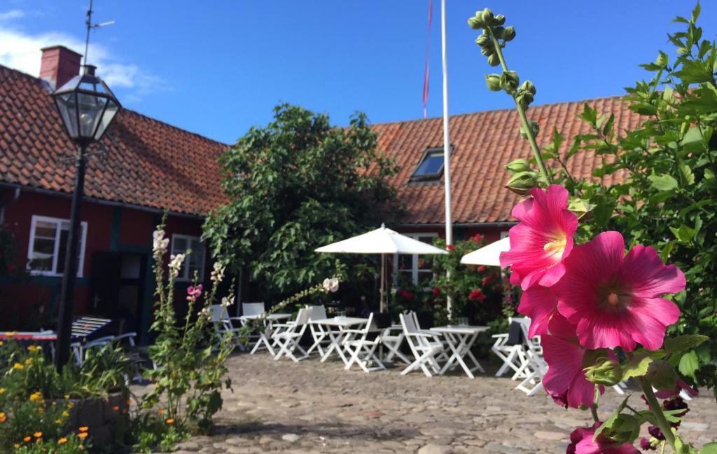 桑德维格Pension Holmegaard的花在一座配有桌子和遮阳伞的建筑前