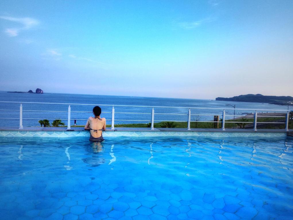 西归浦市日月度假酒店的站在游泳池中望着大海的女人