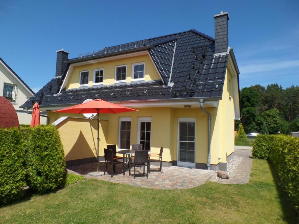 卡尔斯哈根Ferienhaus am Eikboom - DHH2 mit Fasssauna的黄色的房子,配有桌椅和雨伞